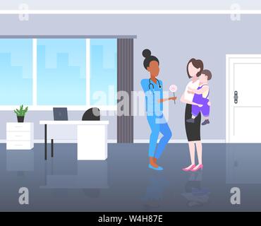 Médecin pédiatre donnant à sucette petit garçon concept soins consultation mother holding baby dans ses mains l'hôpital moderne office interior Illustration de Vecteur