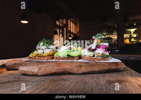 Hors-d'scandinave avec du pain sur une table en bois et en bois d'aliments dans l'élégant café. Des aliments fabriqués avec de l'avocat, le fromage, les amandes, le hareng, les pommes de terre une Banque D'Images