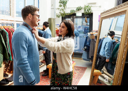 Couple choisissant des vêtements au magasin de vêtements vintage Banque D'Images