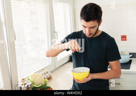 Jeune homme séduisant est le petit-déjeuner dans la cuisine à la maison. Le gars s'est préparé d'avoine et d'un verre de lait pour le petit-déjeuner. Banque D'Images