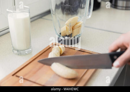 Un jeune homme prépare un smoothie de lait et de fruits frais pour le petit-déjeuner. Il mène une vie saine. Banque D'Images