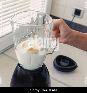 Un jeune homme prépare un smoothie de lait et de fruits frais pour le petit-déjeuner. Il mène une vie saine. Banque D'Images