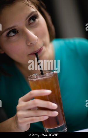 Young adult woman boire d'une paille dans son verre. Banque D'Images