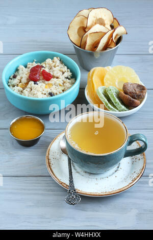 Petit-déjeuner : avoine avec morceaux de fruits confits et de fraises, des morceaux de confit d'ananas, de kiwi et de mangue, figues séchées, de miel et de copeaux de pomme en petits Banque D'Images