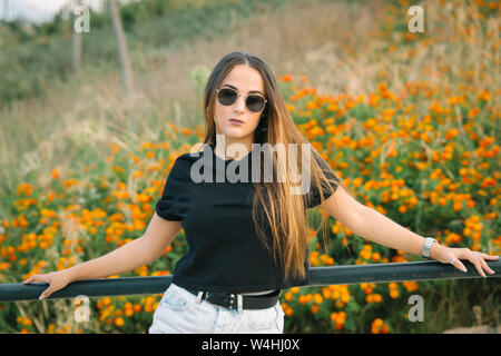 Belle jeune femme posant dans le champ de fleurs Banque D'Images