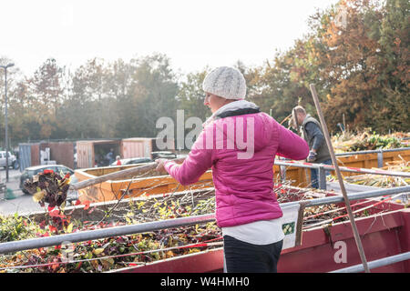 Femme donnant dans le récipient à déchets green recycling center Banque D'Images