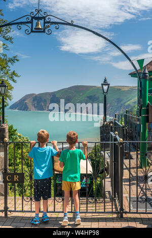 Lynton, Devon, Angleterre. Le mardi 23 juillet 2019. Météo britannique. Avec des températures de planeur sous un ciel bleu, deux petits garçons regarder fasciné comme le 'Lynton et Lynmouth Cliff Railway' descend sur son chemin vers la petite ville portuaire de Lynmouth ci-dessous. Credit : Terry Mathews/Alamy Live News Banque D'Images