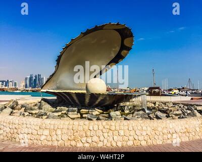 Le monument de la perle, une fontaine avec une sculpture d'huître et de perle, à la Corniche de Doha, Qatar, avec des bateaux et des bâtiments en arrière-plan. Banque D'Images