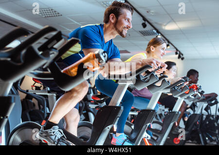 Man et ses amis sur vélo de fitness en salle de sport Banque D'Images