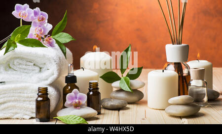 Composition avec fleurs de jasmin et d'orchidée, certaines petites bouteilles avec huiles essentielles, des bougies et de la lumière des pierres pour massage Banque D'Images