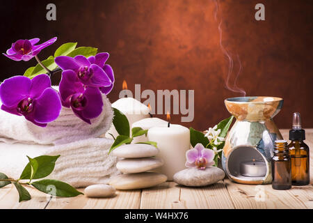 Composition avec fleurs de jasmin et d'orchidée, certaines petites bouteilles avec huiles essentielles, des bougies et de la lumière des pierres pour massage Banque D'Images