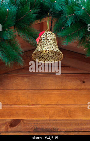 Golden christmas bell qui pendent du toit d'un chalet en bois Banque D'Images