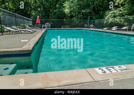 Une piscine avec eau froide calme attente juste pour certaines personnes d'en profiter sur un jour d'été chaud et ensoleillé Banque D'Images