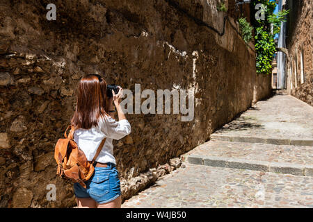 Une jeune touriste rousse prend des photos avec son appareil photo des rues étroites de la vieille ville de Caceres Banque D'Images