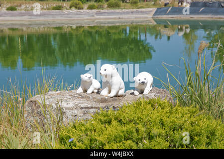 Statue sculptée de l'ours blanc marron avec cub en face de champ de canola sous un lac . Trois ours blanc cub-statue Banque D'Images