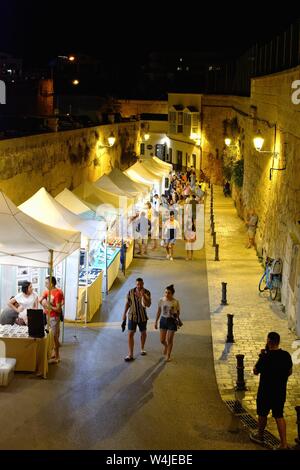 Les étals de marché en plein air animée par les touristes sur la Calle del Portal de la Mar sur une nuit d'été aux Îles Baléares Minorque Ciutadella Espagne Europe Banque D'Images