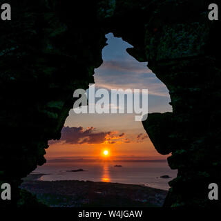 North Berwick, East Lothian, Ecosse, Royaume-Uni, 23 juillet 2019. Météo France : vue depuis le haut de Berwick Law, le noyau d'un volcan éteint qui s'élève au-dessus de la ville, avec un spectaculaire coucher de soleil sur le Firth of Forth par le biais d'un mur en ruine Banque D'Images
