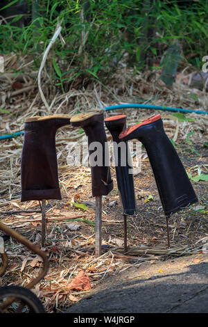 Deux paires de bottes en caoutchouc, bottes Wellington, s'accrocher à l'envers sur des poteaux pour garder les scorpions de pénétrer à l'intérieur. Thaïlande Banque D'Images