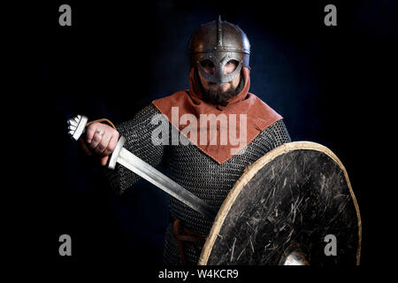 Guerrier Viking dans le courrier, tenant un bouclier et une épée. Sur sa tête est un casque couvrant son visage. close-up. allégorie de la protection, à la sécurité Banque D'Images