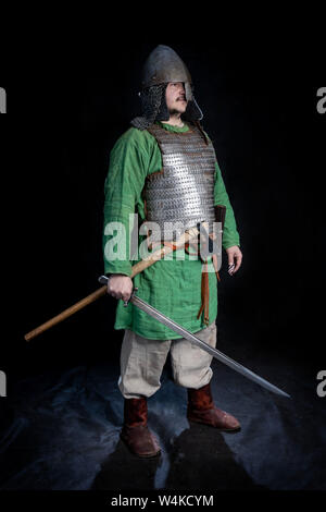 Guerrier slave de l'ère viking, tenant une épée dans ses mains, un casque sur la tête. full length portrait Banque D'Images