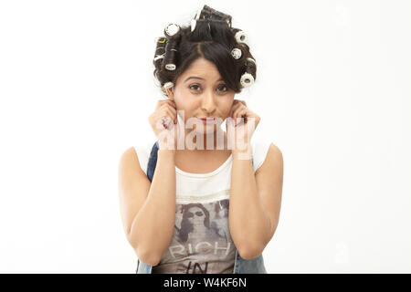 Woman pulling her ears with rollers in hair Stock Photo