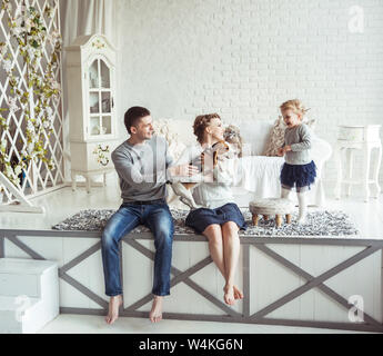 Les parents heureux avec sa fille de cinq ans et leur chien de compagnie dans la salle de séjour Banque D'Images