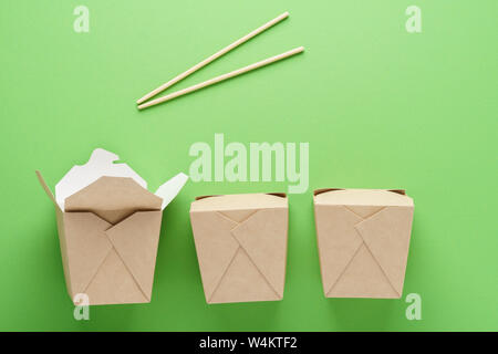 Les boîtes de carton de la nourriture à emporter et baguettes sur fond vert. Livraison Fast food concept. Banque D'Images