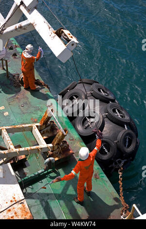 Exploitation minière, gestion et transport des sables bitumineux en titane. L'équipage de la barge abaisse les bouées d'amarrage prêtes à être transportées le long du transporteur de vrac pour décharger la cargaison. Banque D'Images