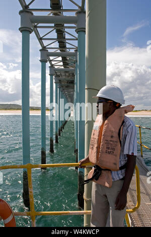 Exploitation minière, gestion et transport des sables bitumineux en titane. Jetée de port avec un travailleur maritime attendant de l'aide pour l'amarrage des barges avant le chargement des produits Banque D'Images