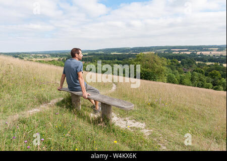 Assise en bois blanchi noueux vieux banc de parc, sur une colline à Chalk grassland plein sud vers Northdowns profitant de la vue et l'ensoleillement Banque D'Images