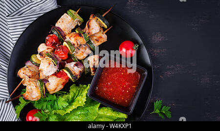 Brochettes de viande grillée, poulet shish kebab avec courgettes, tomates et oignons rouges. Barbecue de la nourriture. Vue d'en haut Banque D'Images