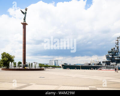 NOVOROSSIYSK, Russie - le 7 juillet 2019 : les touristes sur place avec fontaine Forum Mer Stèle gloire de la Russie et bateau musée cruiser Mikhaïl Koutouzov sur Admir Banque D'Images