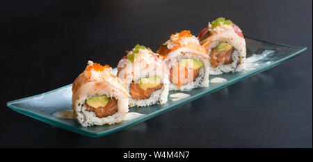 Uramaki spécial, le riz farci au saumon avocat, couverts de sashimi de thon rouge et la mer basse, assaisonné de sauce au fromage, black backgroun Banque D'Images