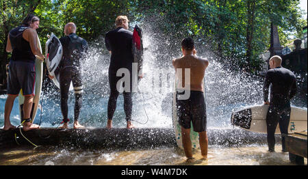 Munich, Allemagne. 24 juillet, 2019. Les surfeurs sont debout dans le jet d'eau d'un surfer au bord de l'Eisbach vague dans le jardin anglais. La vague est un hotspot populaires pour les surfeurs toute l'année. L'Allemagne est confrontée à une vague de chaleur - et déjà le Mercredi ce sera clairement visible dans de nombreux domaines. Crédit : Peter Kneffel/dpa/Alamy Live News Banque D'Images