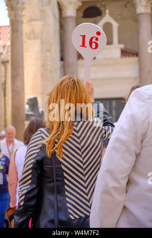 Guide de Voyage femme vu de derrière avec un certain nombre 16 paddle la tête d'un groupe d'anciens à travers la ville européenne Banque D'Images