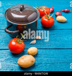 Photo de pot de fer pour la soupe, tomates, pommes de terre, oignons Banque D'Images