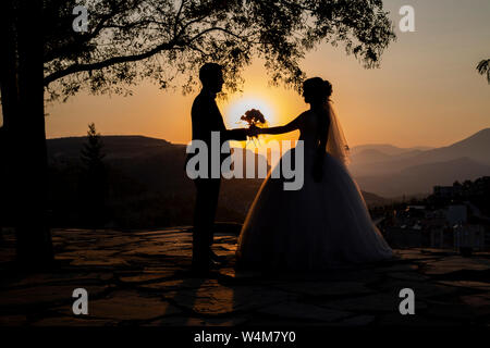 Mariée et marié. Silhouette de mariée et de groom contre le coucher du soleil. Banque D'Images