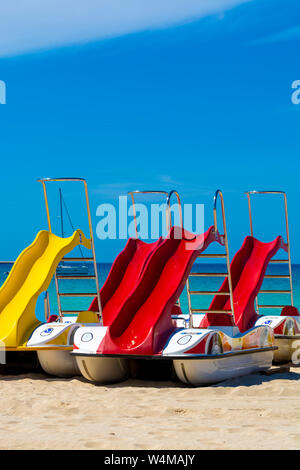 Pédalos colorés avec des toboggans à louer sur la plage de sable avec de l'eau de mer bleue Banque D'Images