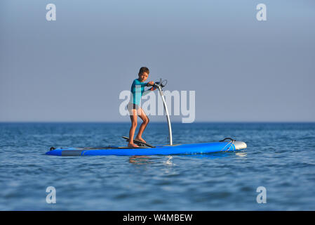 Happy active kid sur un Hobie Stand Up Paddle board Banque D'Images