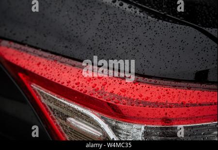 Gouttes de pluie sur la lumière de la voiture noire Banque D'Images