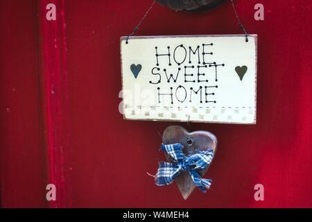 Un mignon Home Sweet Home sign sur une porte rouge vif Banque D'Images