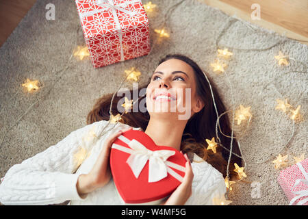 Portrait of gorgeous woman lying on floor rempli de cadeaux de Noël et des lumières Banque D'Images