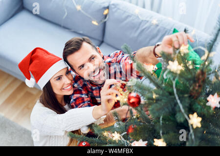 Portrait de joyeux couple decorating Christmas Tree et passer du temps ensemble pendant les vacances Banque D'Images