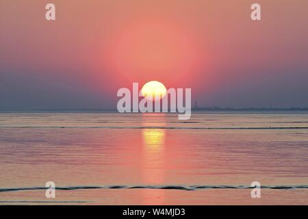 Le soleil est bas et se reflétant dans l'assèchement de couleur rose dans la baie de la mer des Wadden Dollart, 19 avril 2019 | dans le monde entier Banque D'Images