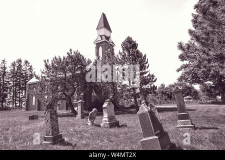 Pays abandonner Grave yard avec ancienne église avec de vieux et tumestones femme priant et en rendant hommage à ses secouristes à sur ses genoux dans le culte. Banque D'Images