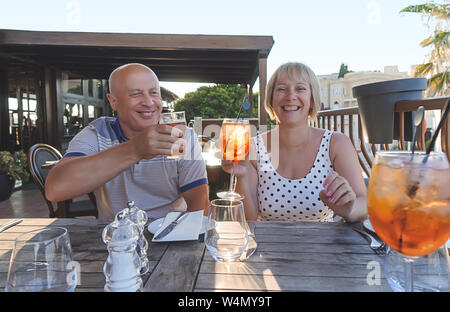 Couple de baby-boomers personnes souriantes et profiter d'un verre au restaurant sur soirée d'été ensoleillé Banque D'Images