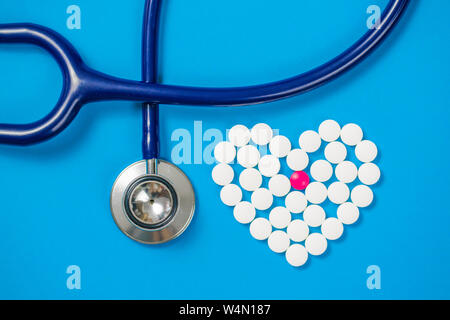 Forme du cœur de pilules blanches et stéthoscope sur papier bleu arrière-plan, Vue de dessus Banque D'Images