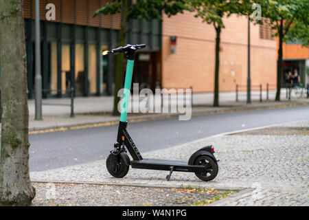 Berlin, Allemagne - juillet 07, 2019 : un scooter électrique vert stationné sous un arbre à Marlene Dietrich Platz avec le théâtre Bluemax dans l'arrière-plan Banque D'Images