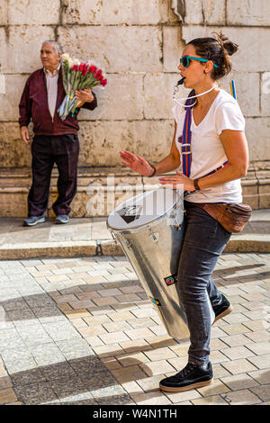 Femme batteur pour protester en mars avec l'homme plus âgé marchande de fleurs en arrière-plan, Malaga, Espagne Banque D'Images