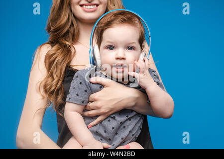 Happy woman with baby boy dans les écouteurs. Banque D'Images